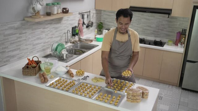 happy asian male homemade cake. portrait of young man put nastar cake on a plastic container box