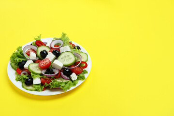Plate of greek salad on yellow background