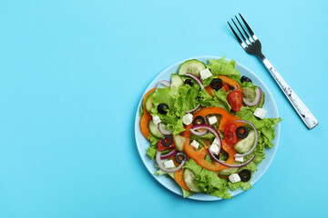 Plate of greek salad and fork on blue background
