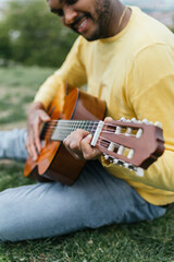 Black man playing guitar in an outdoor park