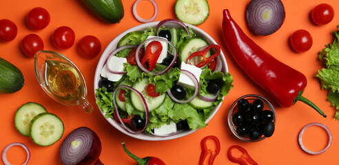 Bowl of greek salad and ingredients on orange background