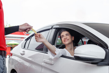 woman in car paying credit card after refuel car ​spending instead of cash with man service employee at gas station. petrol business finance energy concept.