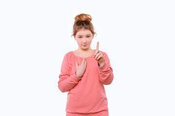 Cute young girl in pink casual sweatshirt points at herself with hand in surprise. White background