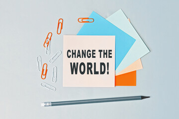 Change the world - text on sticky note paper on gray background. Closeup of a personal agenda