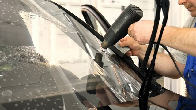Close up of paint protection film installation on modern luxury car. PPF is polyurethane film that wrap car paint to protect paint surface from stone chips, bug splatter, and abrasion.
