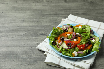 Plate of Greek salad and kitchen towel on gray textured background