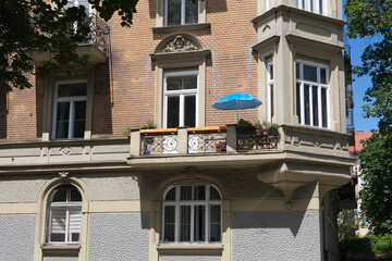 Holiday at home: turquoise parasol on a balcony of an historic building with brick facade © tina7si