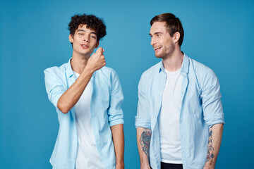 Fototapeta premium Happy friends in identical shirts chatting on a blue background fun model