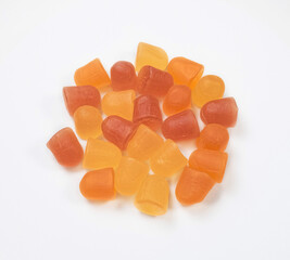 Close-up texture of orange and yellow multivitamin gummies on white background.  Healthy lifestyle...