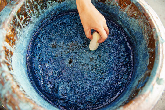 Hand putting the banana into the indigo dye water For providing food for indigo water To preserve the color and not let the water rot , Indigo water focus area