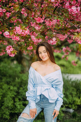 Woman walks in park with blooming sakura trees