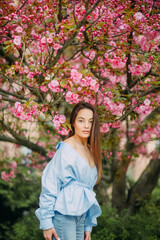 Woman walks in park with blooming sakura trees