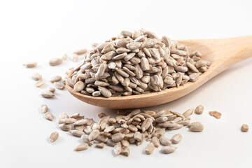 Natural shelled sunflower seeds in wooden spoon isolated on white background. Selective focus