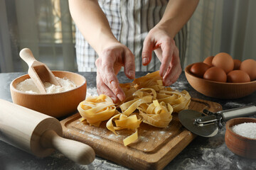 Woman cooking tasty pasta on dark table