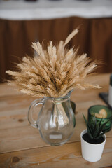 ears of corn in a glass transparent vase on a wooden table in the village, vintage