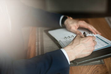 a man in a business suit makes notes in a notebook