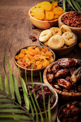 Healthy food snack: sun dried organic mix of dried fruits: apricots, figs, raisins, dates, and other on wooden table, top view