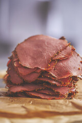 Fresh and delicious stack of sliced pastrami meat placed on wooden cutting board