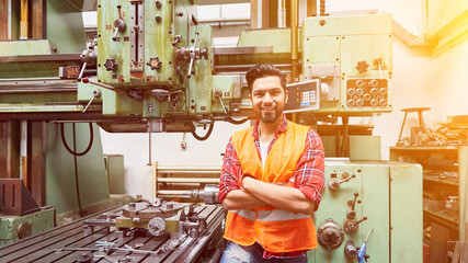 Metal worker at CNC drilling machine in factory