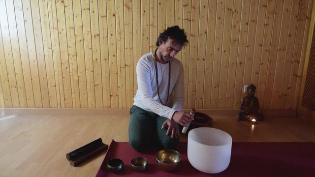an adult man playing 4 different Tibetan bowls