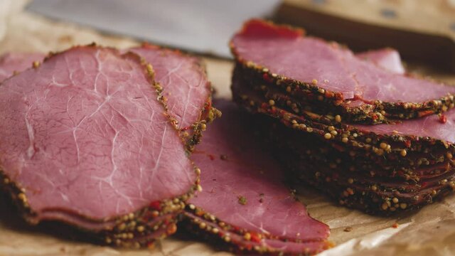 Delicious peppered roast beef pastrami slices on paper with grains of coloured pepper