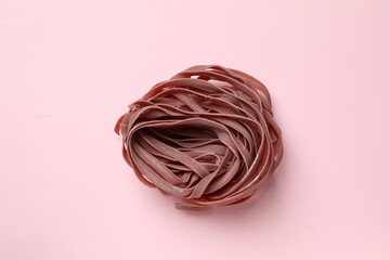 Uncooked pink pasta on pink background, close up