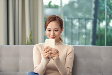 Young asian woman using a smart phone in the room.