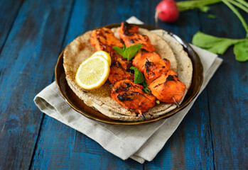 Very juicy and tender grilled chicken tikka or kabab served on a platter with flat bread. Chicken...