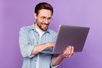 Photo of crazy young happy programmer man look hold laptop work plan isolated on purple color background