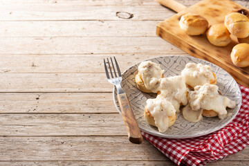 Traditional American biscuits and gravy for breakfast on wooden table. Copy space