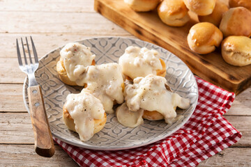Traditional American biscuits and gravy for breakfast on wooden table	