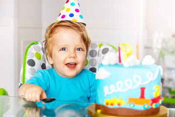 Happy 2 year old toddler sit with birthday cake