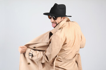 Exhibitionist exposing naked body under coat on light background