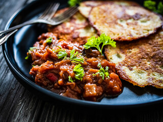 Potato pancakes with vegetable stew on wooden table
