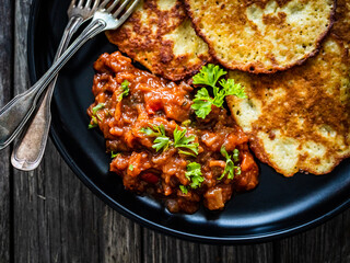 Potato pancakes with vegetable stew on wooden table
