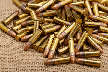 Close up of .22 ammunition on burlap background , .22 LR bullets - obrazy, fototapety, plakaty