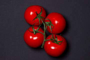Tomatoes on a black background. Tomatoes on a vine on a dark background. Ripe fresh vegetables.