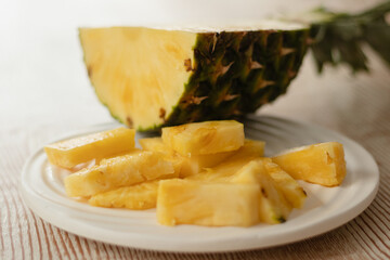 Slices of pineapple on a ceramic white plate, fresh sliced pineapple on a wooden table. Tropical and fruits for breakfast. Vegetarian food.