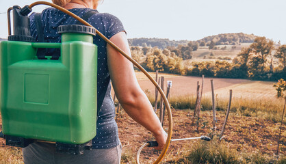 Woman gardening her garden. Spraying pesticide. © Kitja