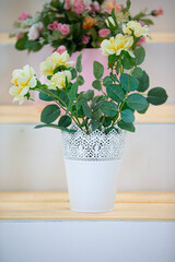 White flower pot with yellow roses.