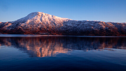 Naklejka premium Snowy mountain in Norwegian sunset.