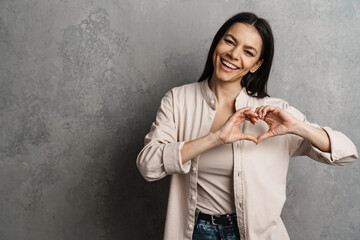 Brunette hispanic woman showing heart gesture and smiling