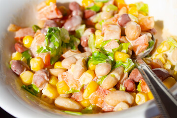 canned bean salad corn tomato greens dressed with mayonnaise in a white plate close-up on the table in sunny weather, sliced vegetables in sour cream dressing, an appetizing lunch, a delicious breakfa