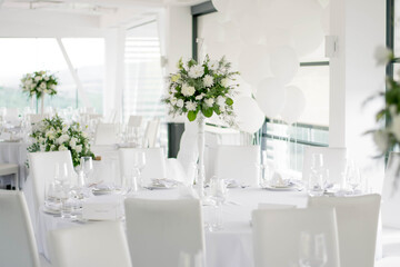 Centerpiece made of green leaves and fresh flowers stands on the dinner table. Wedding day. Fresh flowers decorations.