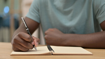 Close up of African Man Writing in Notebook