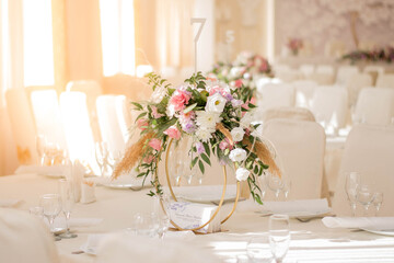 Centerpiece made of green leaves and fresh flowers stands on the dinner table. Wedding day. Fresh flowers decorations.