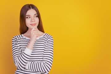 Obraz premium Portrait of thoughtful lady finger chin look empty space on yellow wall