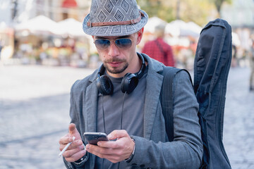 Fototapeta premium Street musician walking with a guitar on his shoulder. Portrait. Music, art, creativity concept. Horizontal image.