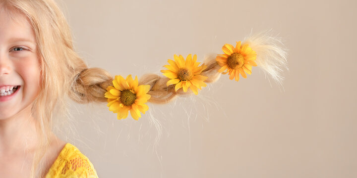 Caucasisn girl close up portrait with yellow flowers in braids.