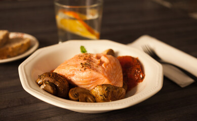simmered slice of salmon with tomato spinon and coconut sauce in a white bowl